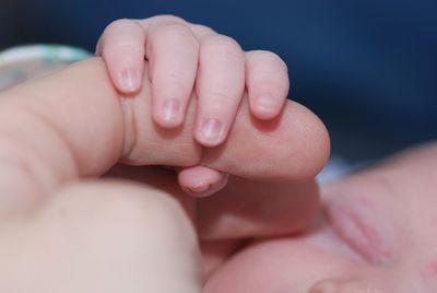 Close-up of newborn holding parents finger