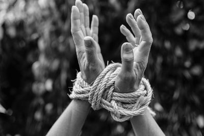 Close-up of human hand against rope