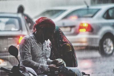 Rear view of woman sitting on street during rainy season