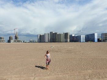 Full length of woman on beach against sky in city