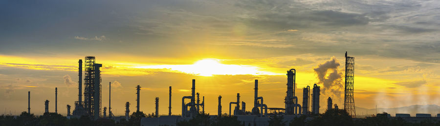 Panoramic view of factory against sky during sunset