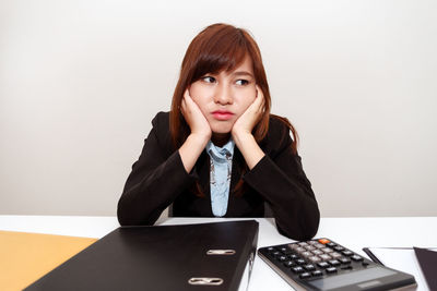 Portrait of young woman using phone while sitting on table