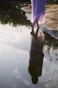 Low section of woman standing on lake