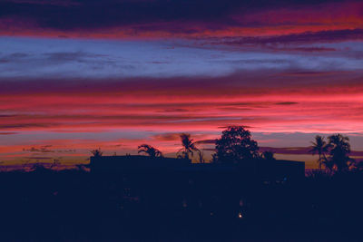 Silhouette trees against dramatic sky during sunset