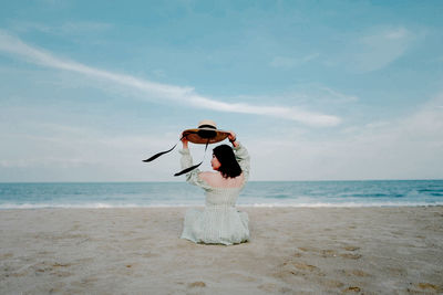 Woman enjoying at beach against sky
