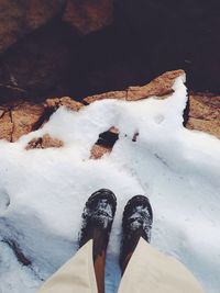 Low section of person standing on snow covered landscape