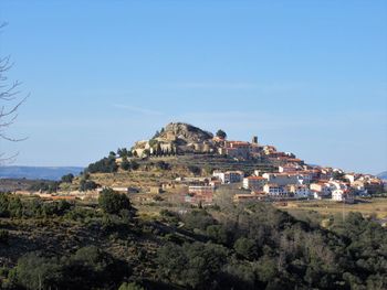 Buildings on mountain against clear blue sky