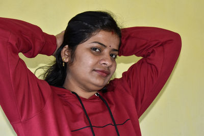 Portrait of young woman with red face against wall