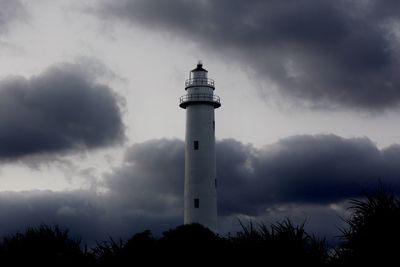 Low angle view of lighthouse by building against sky