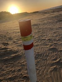 Close-up of wooden post at beach against sky during sunset