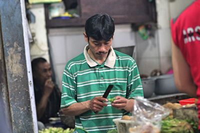 Chef cutting vegetable while standing in commercial kitchen