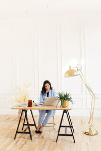 Young woman using laptop while sitting on chair at home