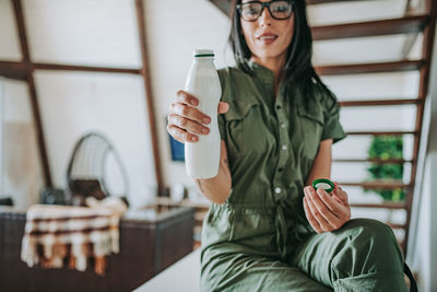 Young woman drinking drink sitting in glass