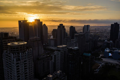 Modern buildings in city against sky during sunset