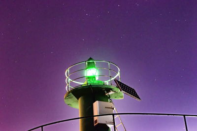 Low angle view of illuminated lighthouse against sky at night