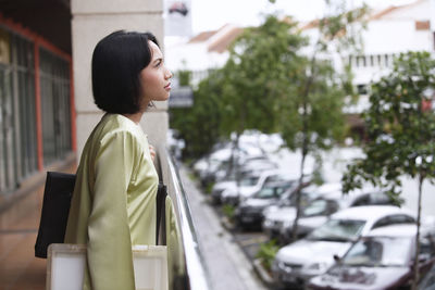 Thoughtful woman holding purse while standing in corridor