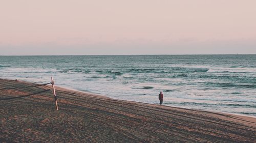 Rear view of man standing on beach during sunset