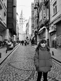 Woman standing on street amidst buildings in city