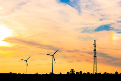 Low angle view of silhouette windmills against sky during sunset