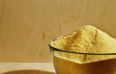 Heap of polenta in glass bowl, yellow grains of cornmeal