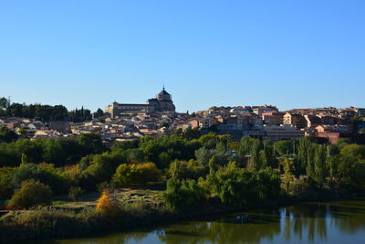 Buildings in city against clear blue sky