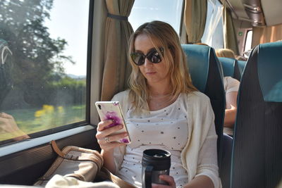 Woman using mobile phone while sitting in bus