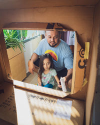 Father and child painting recyled cardboard together.