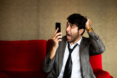 Young man using mobile phone on sofa