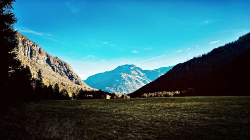 Scenic view of field and mountains against blue sky