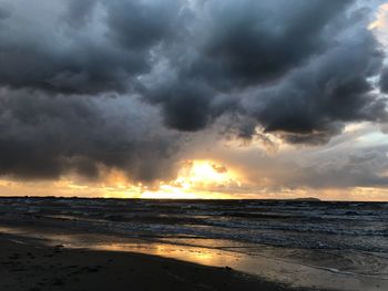 Scenic view of sea against dramatic sky during sunset