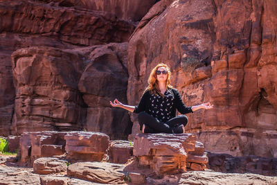 Woman wearing sunglasses sitting on rock