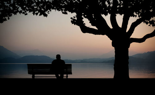Silhouette of people sitting on lakeshore