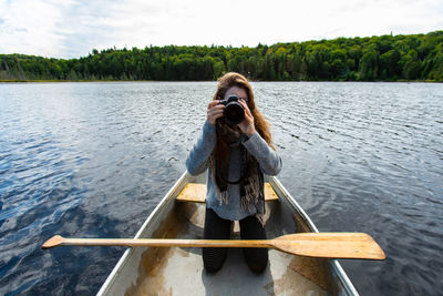 Man photographing while standing on lake