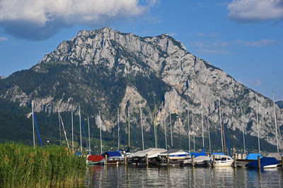 Sailboats moored in sea against sky