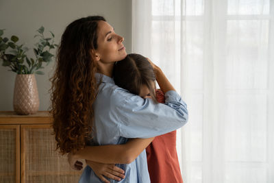 Young woman looking away while standing at home