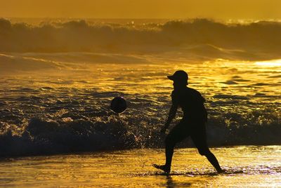 Silhouette of woman standing on beach at sunset