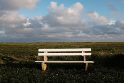 View of an empty bench on field against sky