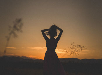 Silhouette woman standing against sky during sunset