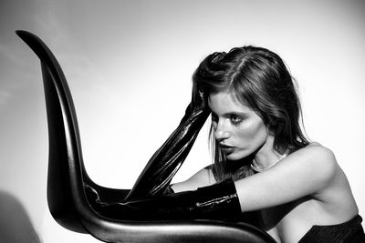 Portrait of young woman looking away against wall