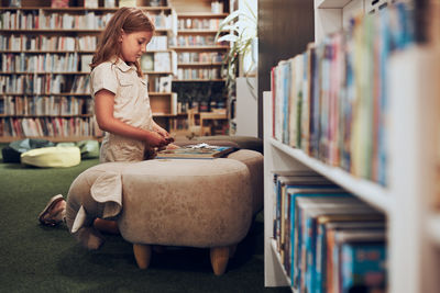 Schoolgirl doing puzzle and reading book in school library. primary school girl is involved in book