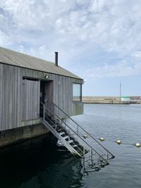 Pier over lake by building against sky