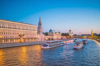 Boats in river with buildings in background