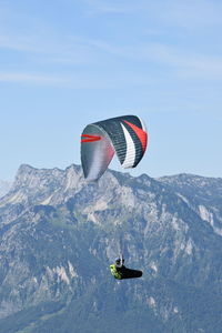 People paragliding over snowcapped mountain against sky