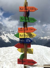 Information sign on snowcapped mountains against sky