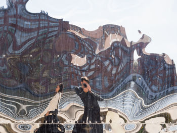 Rear view of people standing against built structure