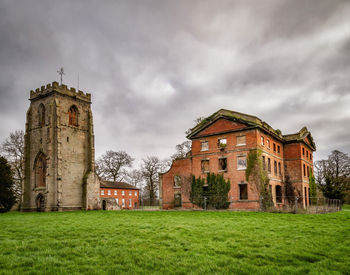 Old building on field against cloudy sky