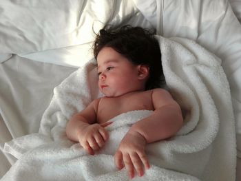 High angle view of cute baby lying on bed at home