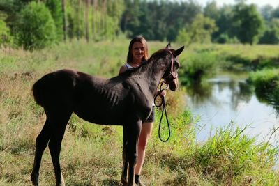Portrait of young woman standing with horse on land