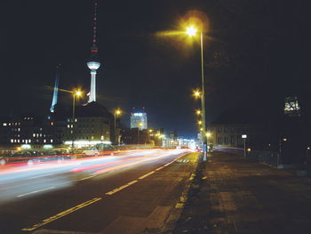 Light trails on road against sky in city at night