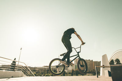 Side view of man riding bicycle against clear sky